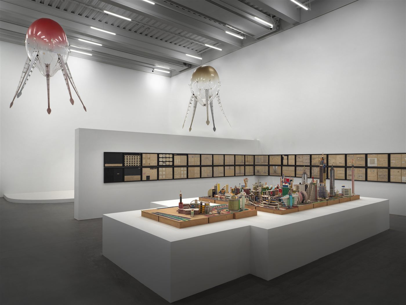 Aerobes suspended above an artist's model cityscape at the New Museum