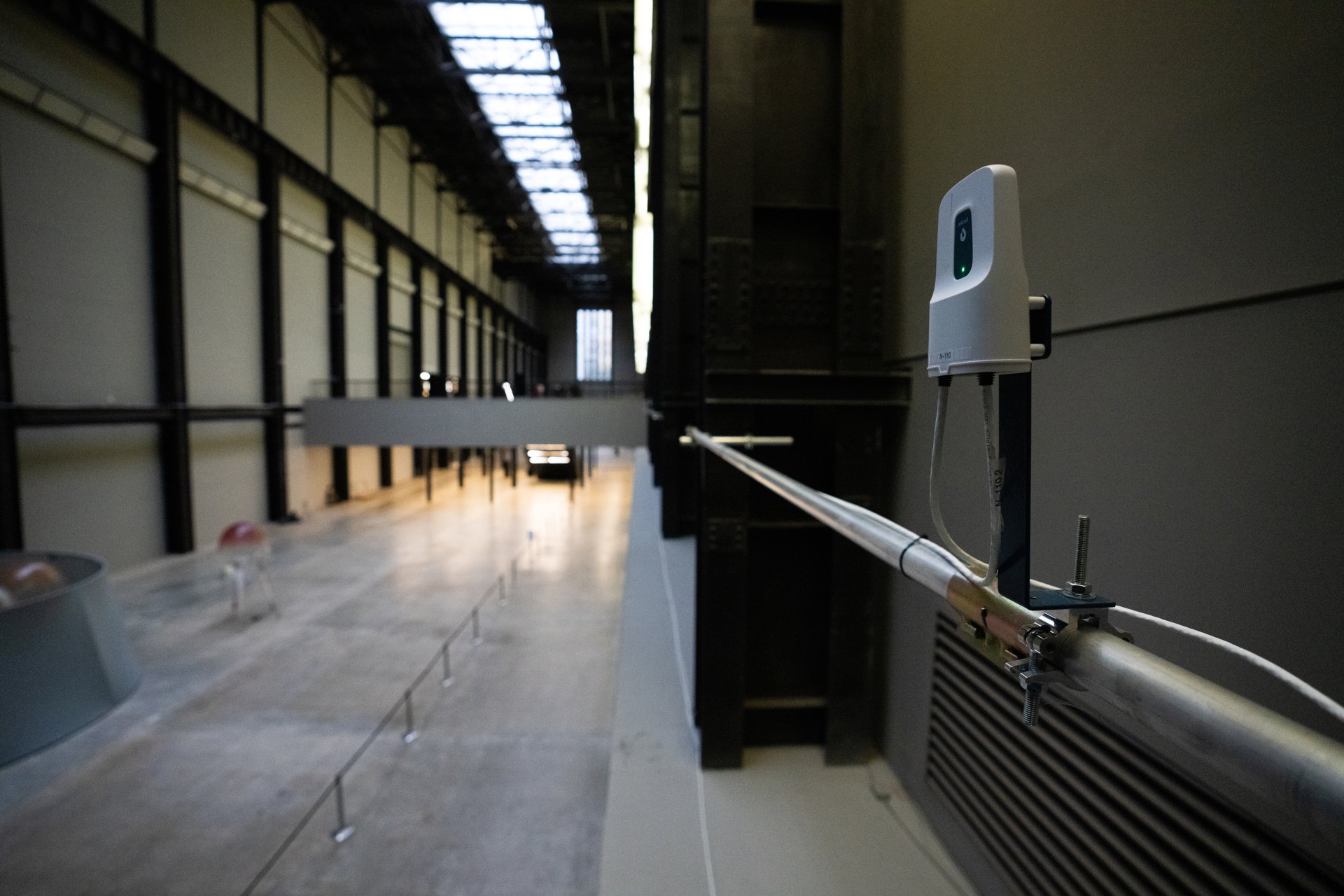 A UWB anchor mounted on a pole overlooking the Turbine Hall walkway, with the aerobe base station visible in the background