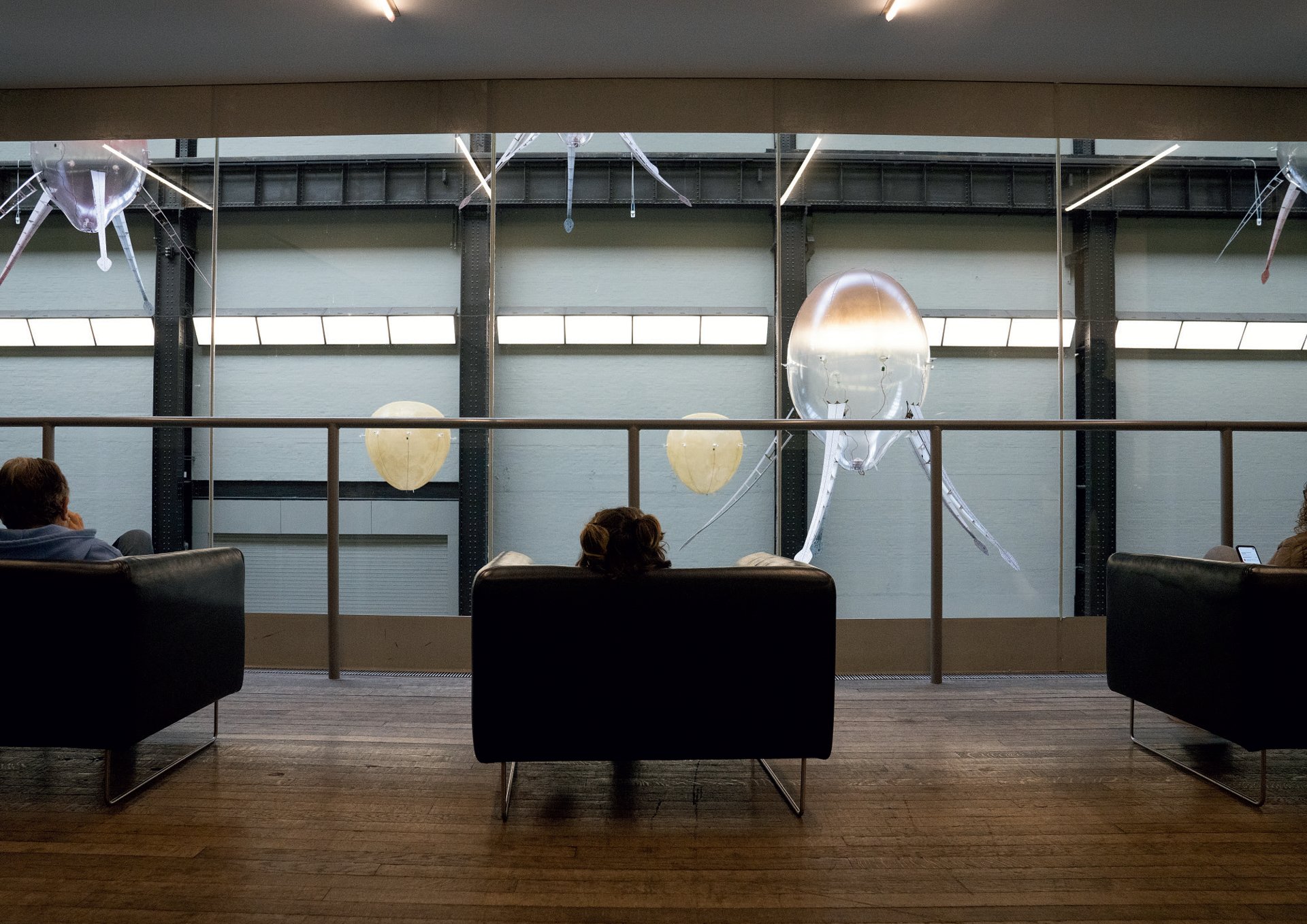 Visitors seated in the Turbine Hall gallery, watching aerobes drift past at close range